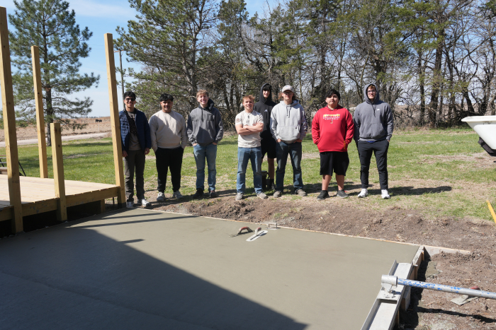 8 male students standing and smiling at a construction site